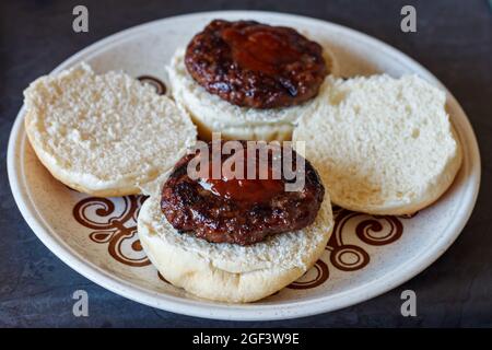 due hamburger freschi grigliati alla fiamma su panini bianchi Foto Stock