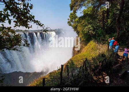 I turisti che guardano le magnifiche Cascate Vittoria una delle destinazioni turistiche più popolari, lo Zimbabwe Foto Stock