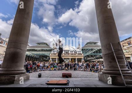 Un animatore di strada ama esibirsi di fronte a grandi folle a Covent Garden Piazza, nel centro di Londra, Inghilterra, Regno Unito Foto Stock