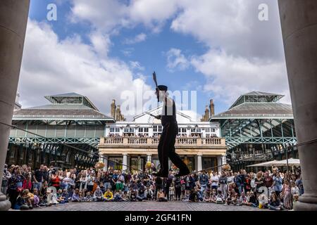 Un animatore di strada ama esibirsi di fronte a grandi folle a Covent Garden Piazza, nel centro di Londra, Inghilterra, Regno Unito Foto Stock