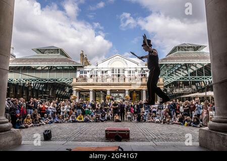 Un animatore di strada ama esibirsi di fronte a grandi folle a Covent Garden Piazza, nel centro di Londra, Inghilterra, Regno Unito Foto Stock