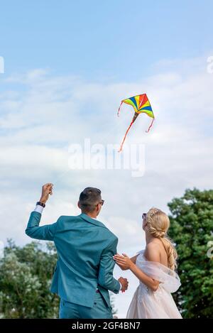 Un aquilone ad un matrimonio. Una coppia di nozze lancia un aquilone nel cielo. Sposi e sposi volano un aquilone insieme il loro giorno di nozze. Foto Stock