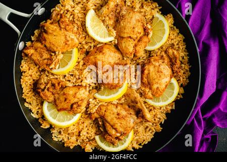 Una padella di pollo e riso spagnolo in una zattera: Cosce di pollo e riso condito con paprika affumicata, aglio e altre spezie Foto Stock