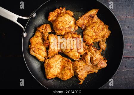 Cosce di pollo rosolate con condimento spagnolo in un Skillet: Cosce di pollo rosolate e riso con paprika affumicata, aglio e altre spezie Foto Stock