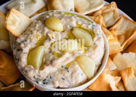 Salsa di fagioli bianchi all'aglio e rosmarino arrosto: Salsa a base di fagioli cannellini, olio d'oliva e aglio arrostito servito con patatine pita Foto Stock