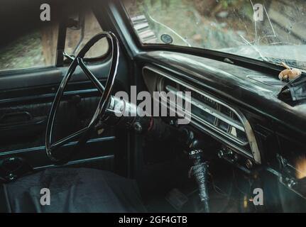 Primo piano dall'interno di un'auto d'epoca con parabrezza rotto Foto Stock