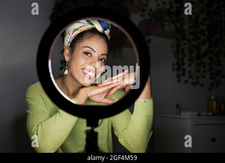 Donna sorridente che indossa la fascia che guarda attraverso la luce ad anello illuminata Foto Stock