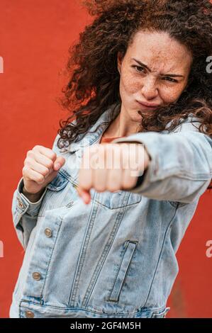 Giovane donna che puncia con pugno mentre fa il viso Foto Stock