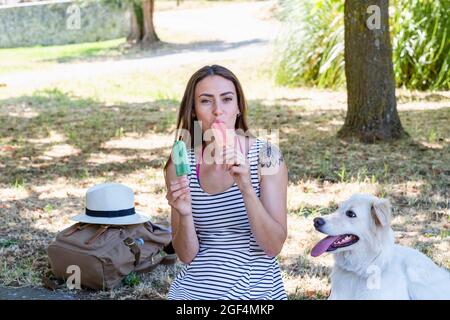 Donna che mangia gelato mentre si siede da cane Foto Stock