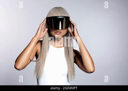 Donna che indossa occhiali futuristici visiera su sfondo bianco Foto Stock