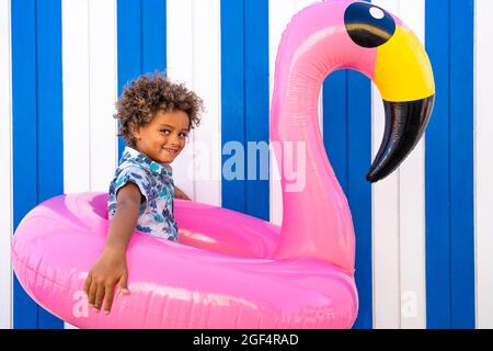 Ragazzo carino che gioca con il flamingo rosa gonfiabile Foto Stock