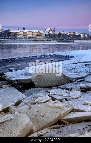 Polonia, Voivodeship Masoviano, Varsavia, ghiaccio galleggiante sul lungofiume all'alba con edifici della città vecchia sullo sfondo Foto Stock
