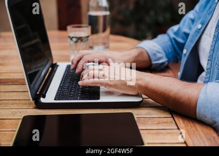 Libera professionista di sesso maschile che lavora su un computer portatile alla scrivania Foto Stock