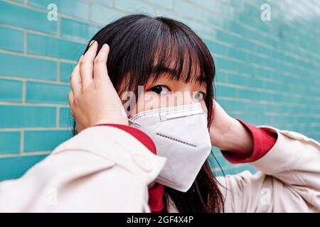 Donna che copre le orecchie mentre indossa maschera protettiva per il viso Foto Stock