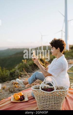 Donna che prende selfie attraverso lo smartphone durante il picnic Foto Stock