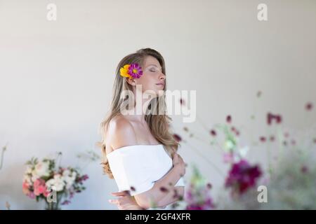 Giovane donna con margherita giallo e viola in capelli in studio Foto Stock