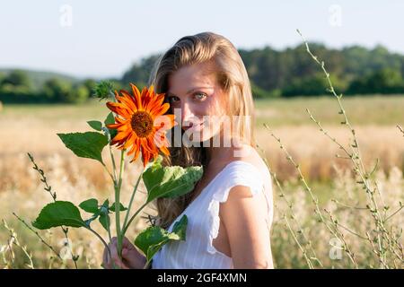 Bella giovane donna con girasole in campo Foto Stock