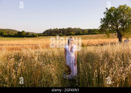 Giovane donna che tiene il cappello in campo Foto Stock