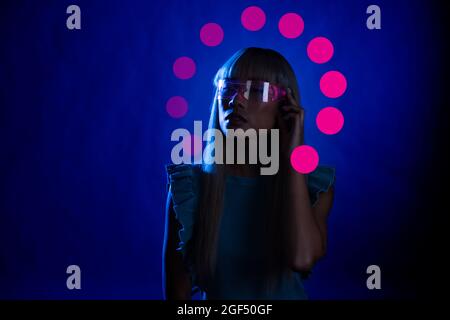 Giovane donna che indossa occhiali eleganti su sfondo blu Foto Stock