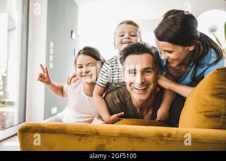 Donna che guarda l'uomo mentre gioca con figlio e figlia sul divano a casa Foto Stock