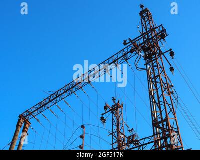 Poli elettrici ferroviari con fili su sfondo cielo blu Foto Stock
