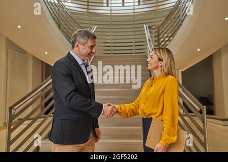 Partner commerciali maschili e femminili che fanno handshake in ufficio Foto Stock