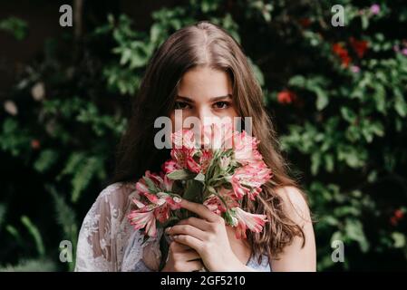 Giovane donna che odora fiori freschi Foto Stock