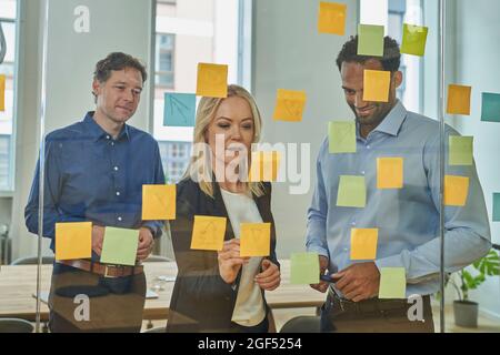 I professionisti aziendali pianificano la strategia su appunti adesivi nella sala del consiglio di amministrazione dell'ufficio Foto Stock