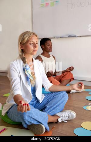 Donna d'affari che fa yoga con un collega in ufficio Foto Stock