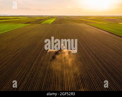 Vista aerea del trattore che irrorano colture di soia al tramonto Foto Stock