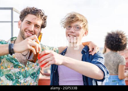 Amici sorridenti che tostano bevande durante la festa Foto Stock