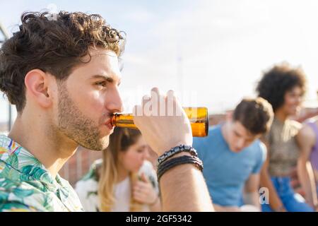 Giovane uomo che beve birra durante la festa Foto Stock