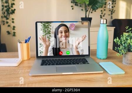 Una freelance femminile che gesturing durante la videoconferenza attraverso un portatile in ufficio a casa Foto Stock