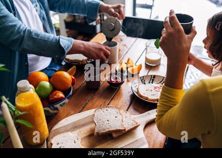 Uomo che prepara il caffè mentre fa colazione con la famiglia a casa Foto Stock