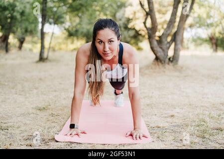 Atleta femminile che fa push-up nella foresta Foto Stock