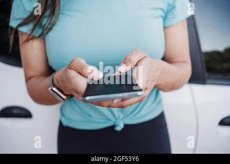 Messaggi di testo per le giovani donne tramite smartphone all'esterno dell'auto Foto Stock