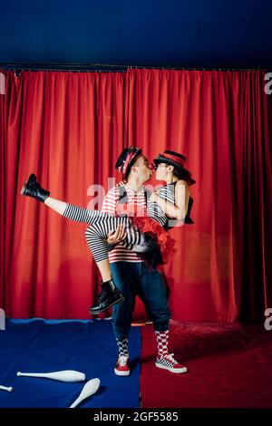 Maschio e femmina clown baciare mentre si esibiscono sul palcoscenico del circo Foto Stock