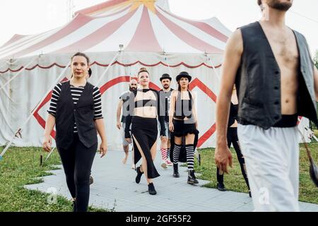 Artisti maschili e femminili che camminano all'esterno della tenda del circo Foto Stock