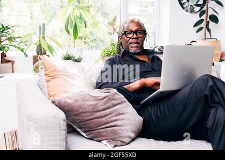 Uomo d'affari seduto sul divano con un computer portatile a casa Foto Stock