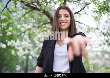 Felice bella giovane donna che raggiunge al parco pubblico Foto Stock