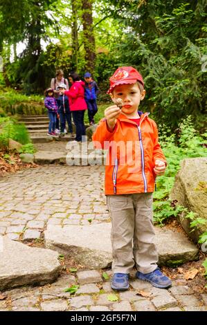 P, POLONIA - 23 maggio 2021: Un ragazzino carino in piedi su un sentiero e che tiene una lumaca Foto Stock
