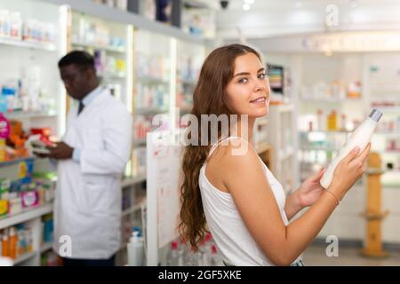 Teenager girl scelta dei prodotti haircare in farmacia Foto Stock