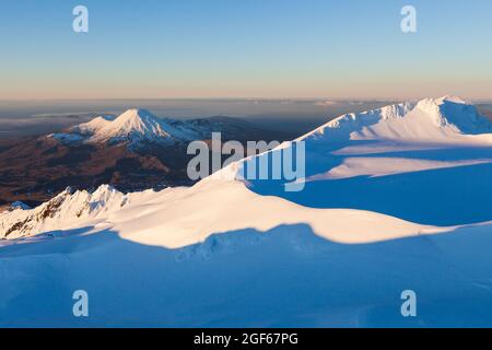 Vista dal Monte Ruapehu, attraverso l'altopiano sommitale per te Heu Heu e Tukino sub cime e per il Monte Ngauruhoe e Tongariro, Whakapapa skifield a sinistra Foto Stock