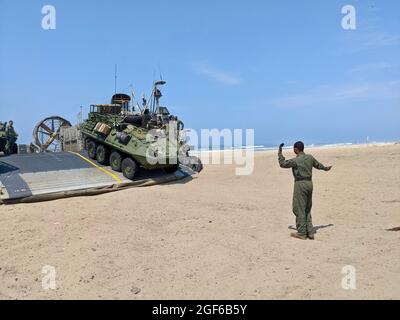 Il Mate Third Class Chazz Lewis di Boatswain, un loadmaster a cuscino d'aria dell'imbarcazione da atterraggio (LCAC) assegnato all'unità cinque dell'Artigianato d'Assalto (ACU-5), guida i veicoli blindati (LAV) fuori da una LCAC durante la formazione congiunta tra l'ACU-5 e la Light Armored Reconnaissance Training Company (LARTC), Advanced Infantry Training Battalion West (AITBW). Foto Stock