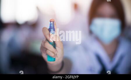 Uniforme studente indossare maschera facciale e tenere alcol spray per proteggere covid-19 a scuola Foto Stock