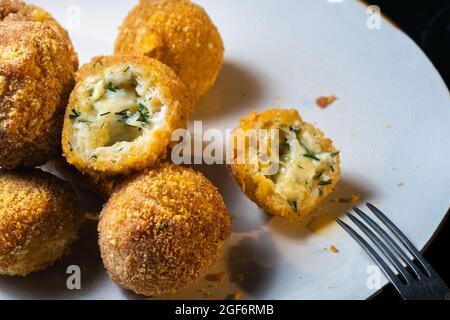 palle di formaggio con aneto interno per uno spuntino in un piatto su sfondo nero. Foto Stock