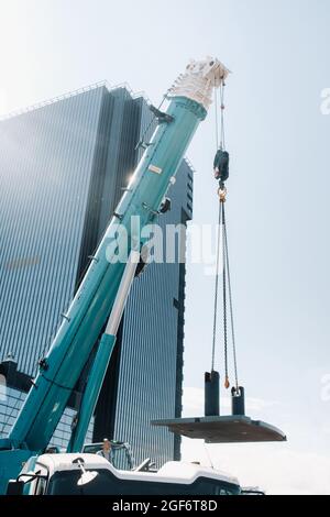 la stufa viene caricata su una grande gru blu per auto e preparata per il funzionamento . La gru per camion più grande per la risoluzione di attività complesse Foto Stock