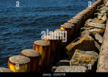 Pali di acciaio che proteggono la banchina del porto. Foto scattata in buone condizioni di illuminazione in una giornata di sole Foto Stock