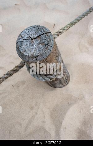 Un palo di legno con corde allungate che separano il sentiero dall'area protetta. Foto scattata in buone condizioni di illuminazione in una giornata nuvolosa Foto Stock