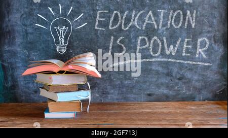 libri e lavagna con disegno di una lampadina e slogan educazione è potere, apprendimento, conoscenza, ritorno a scuola concetto Foto Stock